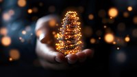 Magical glowing Christmas tree made of golden lights and sparkles floating above open palm against dark background with bokeh effect and light particles.