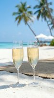 Two champagne flutes filled with sparkling wine on tropical beach with palm trees and turquoise ocean for luxury vacation celebration and romantic getaway.