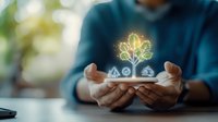 Young Asian businessman holding smartphone with glowing tree hologram, representing sustainable business growth and eco-friendly technology solutions.