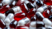 Red and white medical capsules and pills in macro view showing pharmaceutical texture and pattern, healthcare and medicine concept background.