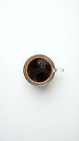 Glass mug of hot black coffee with steam rising on white background, top view flat lay for morning beverage and cafe menu design.