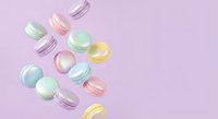 Colorful macarons floating on pastel pink background, French pastry dessert cookies in mint green, yellow and purple colors for bakery menu design.
