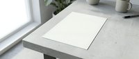 Blank white paper sheet on concrete desk near window with natural light, minimalist workspace setup for mockup and branding projects.