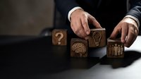 Business strategy concept with wooden blocks featuring brain, lightbulb and chart icons arranged by professional hands for corporate planning solutions.