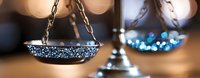 Scales of justice with sparkling blue glitter against blurred bokeh background, symbolizing law, balance, and legal system in modern artistic interpretation.