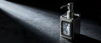Elegant glass soap dispenser with metallic pump on dark textured surface with dramatic lighting for modern bathroom and kitchen design concepts.