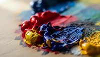 Colorful oil paint tubes squeezed onto artist palette with mixed pigments creating vibrant abstract composition for creative artwork and painting projects.