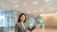 Woman in business attire holding smartphone with floating digital communication icons including user profiles and chat bubbles in modern office environment for corporate technology concepts.