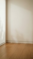 Empty room corner with natural sunlight streaming through window onto beige wall and wooden floor for interior design projects.