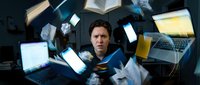 Overwhelmed businessman surrounded by floating laptops, tablets and documents in dark space representing digital overload and work stress.