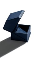Open navy blue gift box with lid partially lifted revealing empty interior on white background with dramatic shadow for luxury packaging design.