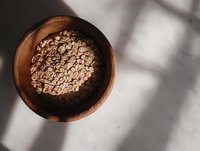 Rolled oats in wooden bowl with natural sunlight and shadows creating minimalist composition. For healthy lifestyle, cooking and food photography.