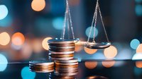 Stacked coins beside justice scales against blurred city lights background, symbolizing financial balance, law and economy concepts.