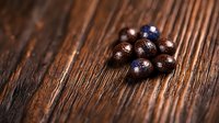 Fresh dark chocolate truffles with cocoa powder dusting scattered on rustic wooden background, selective focus creating depth and texture for food photography.
