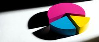 Colorful CMYK pie chart with magenta, cyan, yellow segments casting shadow on white surface for business presentations and data visualization.