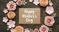 Happy Mother's Day greeting card surrounded by pink paper flowers on rustic wooden background. Handmade craft design for mom celebration and spring holiday.