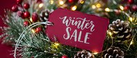 Red winter sale tag on festive Christmas wreath with pine cones, berries, and glowing lights, perfect for holiday retail promotions.