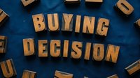 Wooden block letters spelling buying decision on textured blue background, representing consumer choice, commerce, and retail strategy for business and marketing concepts.