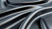 Smooth waves of dark gray satin fabric create elegant folds and curves with soft shadows and highlights, suitable for luxury product backgrounds and fashion designs.