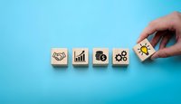 Hand placing wooden cube with lightbulb icon completing business strategy sequence on blue background for corporate planning and innovation concepts.