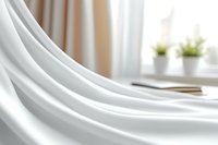 Soft white fabric with elegant folds and gentle curves creates luxurious textile background. Natural window light adds depth to smooth flowing material.