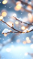 Snow-covered tree branches against blue winter sky with golden bokeh lights and falling snowflakes creating magical seasonal atmosphere.