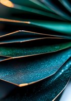 Macro photography of metallic turquoise surfaces with water droplets creating abstract geometric pattern. Golden edges catch light against dark background for dramatic effect.