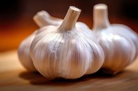 Fresh garlic bulbs with papery white skin on wooden surface. Organic cooking ingredients for culinary preparations and healthy Mediterranean cuisine.