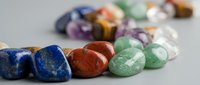 Collection of polished gemstones and healing crystals including lapis lazuli, jasper, and aventurine arranged on neutral background for wellness practices.