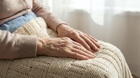 Senior woman hands resting on knitted blanket in warm natural light. Elderly care, comfort, relaxation, aging gracefully, cozy home atmosphere concept.
