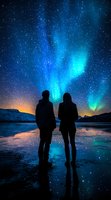 Silhouettes of couple watching northern lights dance across starry night sky, reflected in frozen lake surface against snowy mountain backdrop in magical blue glow.