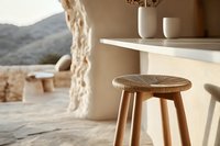 Minimalist wooden bar stool with carved seat pattern in modern interior space featuring natural light, mountain views and neutral earth tones. Cozy home design setting.