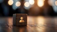 Wooden cube with user profile icon on dark surface against blurred bokeh lights background, symbolizing social media and digital identity concepts.