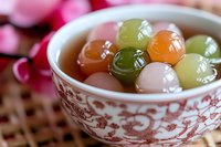 Colorful Asian dessert balls made from rice flour in traditional porcelain bowl with oriental pattern, sweet mochi dumplings in syrup served as traditional treat.