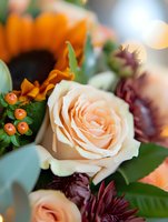 Peach rose bloom among burgundy dahlias and orange berries in romantic autumn bouquet with soft bokeh background, macro floral photography.