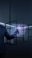 Businessman in dark suit interacting with holographic digital interface displaying analytics and strategic data visualization in modern office environment.