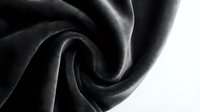 Luxurious black silk fabric with elegant flowing curves and soft draping folds creating dramatic shadows and highlights for fashion and textile design projects.