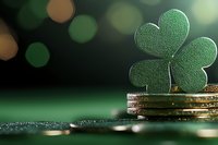 Green paper shamrock on stack of gold coins against dark background with bokeh lights, celebrating Irish luck and prosperity. St Patrick's Day concept.