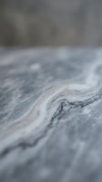 Close-up macro view of natural gray marble stone surface with intricate veining patterns and smooth polished texture for luxury interior design projects.
