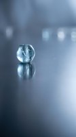 Single crystal clear glass sphere with frozen ice formations inside, reflecting light on soft blurred background. Suitable for abstract, science, and winter-themed designs.