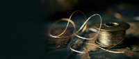 Golden metallic ribbon curls elegantly on dark surface with warm lighting creating luxury gift wrapping and celebration atmosphere for holidays.