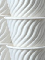 White ceramic cups with diagonal ribbed texture pattern stacked together creating modern minimalist kitchen composition for coffee shop branding and tableware design.