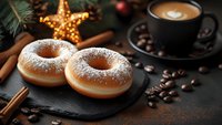 Sugar powdered donuts on black slate with coffee cup, cinnamon sticks, coffee beans and glowing star decoration in cozy Christmas setting against dark background.
