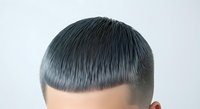 Rear view of male with short dark hair and modern blunt fringe haircut against white background, suitable for hair salon marketing and grooming design projects.