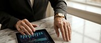 Professional businessman analyzing financial data on tablet device at modern office desk for business strategy and investment planning decisions.