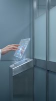 Hand touching futuristic transparent digital interface screen in modern elevator with holographic display technology for smart building control systems.