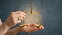 Female hands holding golden scales of justice symbol representing legal balance and fairness in law and court proceedings.