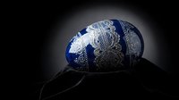 Ornate blue and silver decorative egg with intricate metallic patterns on dark background for luxury design projects and elegant seasonal displays.