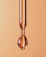 Glass dropper with golden serum drop against warm beige background for skincare cosmetics and beauty product packaging design.