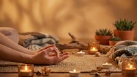 Peaceful meditation session with candles and plants creating serene wellness atmosphere for relaxation and mindfulness practice at home.